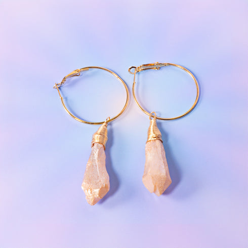 a pair of gold hoop earrings with a stone drop